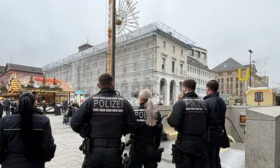 Polizeibeamte und Fahrscheinprüfer stehen am Zugang zu der Stadtbahntunnel-Haltestelle am Karlsruher Marktplatz. Im Hintergrund ist der Weihnachtsmarkt zu sehen. 