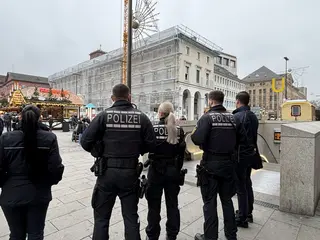 Polizeibeamte und Fahrscheinprüfer stehen am Zugang zu der Stadtbahntunnel-Haltestelle am Karlsruher Marktplatz. Im Hintergrund ist der Weihnachtsmarkt zu sehen. 