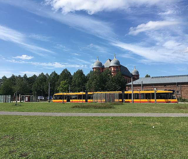 Straßenbahn fährt hinter einem grünen Feld