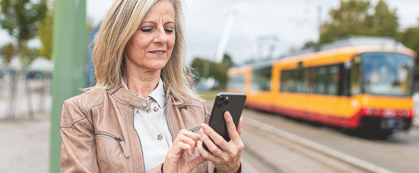 Frau steht mit Bandy vor der Bahn