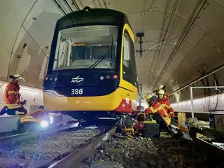 Feuerwehrmänner heben mithilfe von Spezialgerät eine Straßenbahn nach oben.