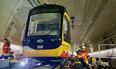 Feuerwehrmänner heben mithilfe von Spezialgerät eine Straßenbahn nach oben.